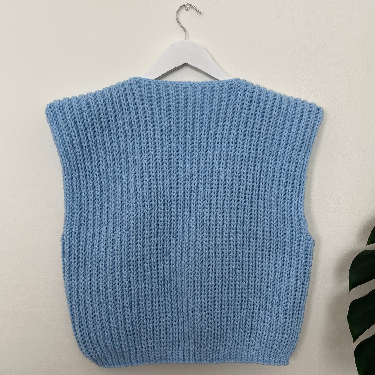 Blue knitted sweater on a hanger against a white background